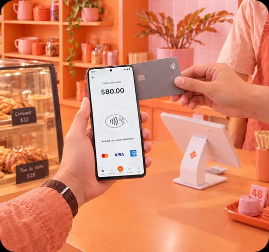 Cliente paga con tarjeta en un celular con Tap to Pay en una panadería